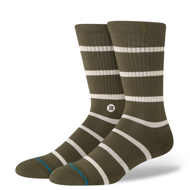 Pair of green stance butter blend crew socks with white stripes on a white background