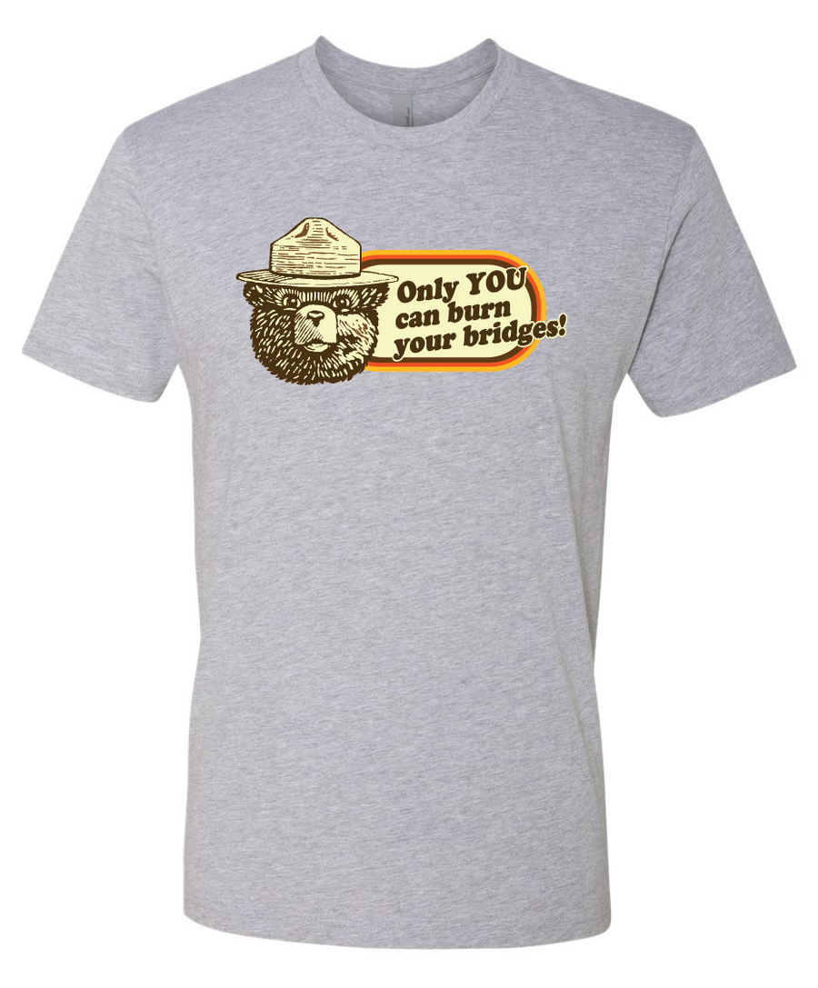Gray t-shirt with a graphic design featuring a smokey the bear and text that reads only you can burn your bridges on a white background