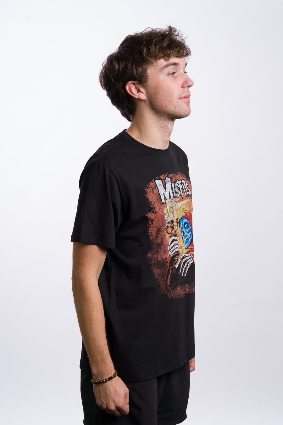 Person wearing a black t-shirt with 'Misfits' graphic design on a white background
