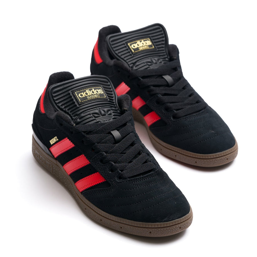 black adidas busentiz men's skate shoes with three orange stripes and a gum sole