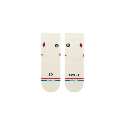 A pair of Stance crew socks in off-white, featuring a black circular logo with a white cross on the front ankle, a small red strawberry graphic on the side, and red and blue wavy stripe accents near the toe.