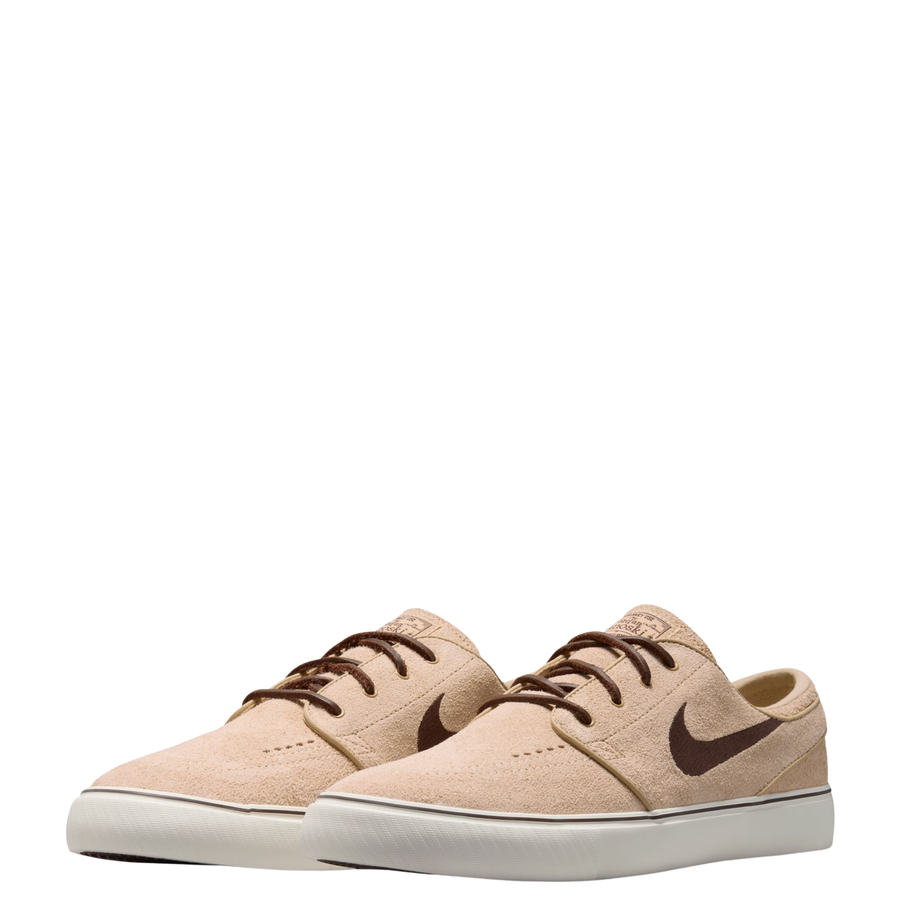 A Nike sb janoski low-top sneaker in a light beige suede and canvas mix, featuring a dark brown Swoosh logo, matching brown laces, and a thick white rubber sole.