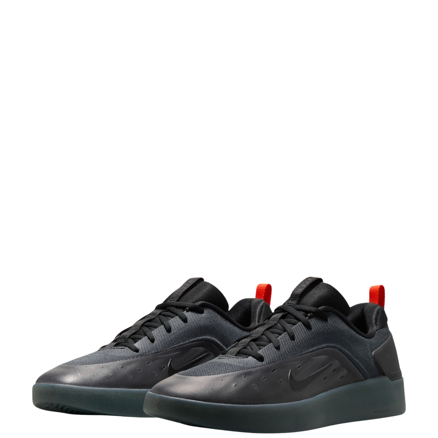 A black Nike nyjah 4 skateboard sneaker with a textured synthetic upper, black laces, a black sole, and a small red pull tab on the heel, shown from a side profile against a white background.