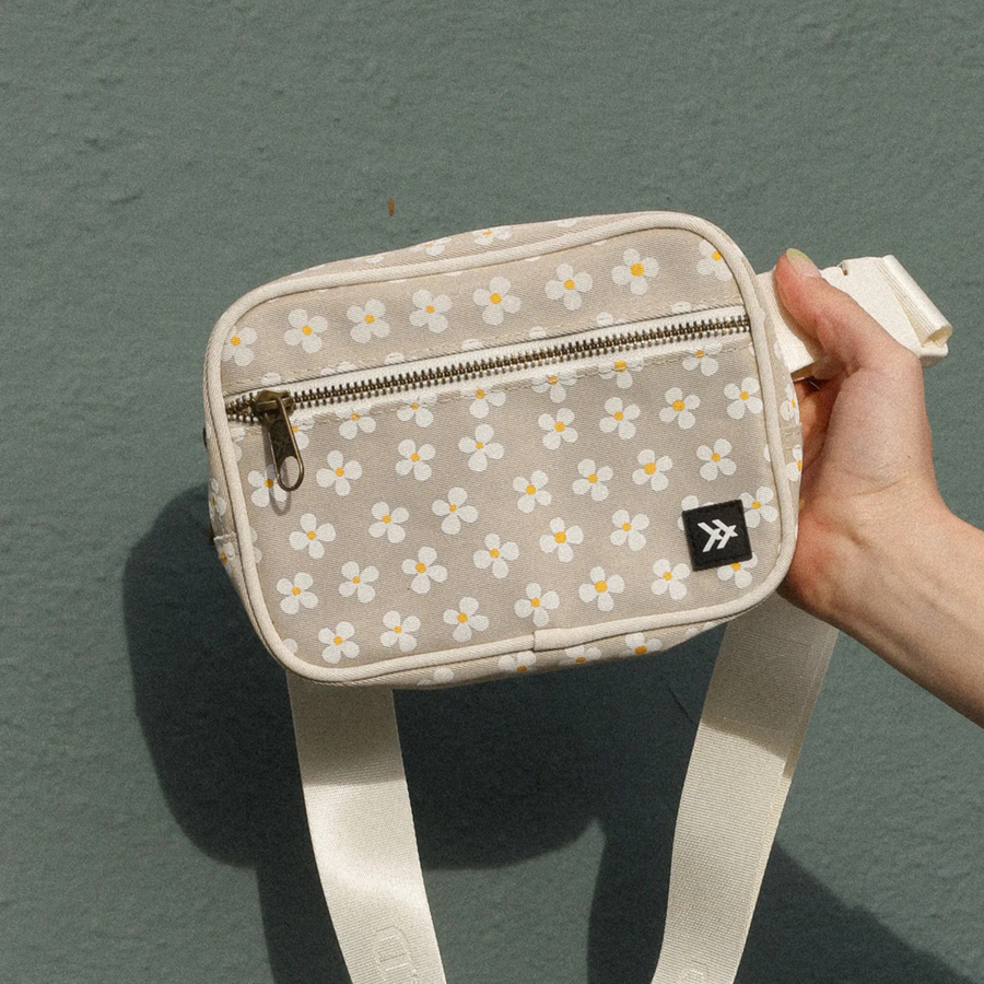 Beige belt bag with floral pattern and thread logo on a white background