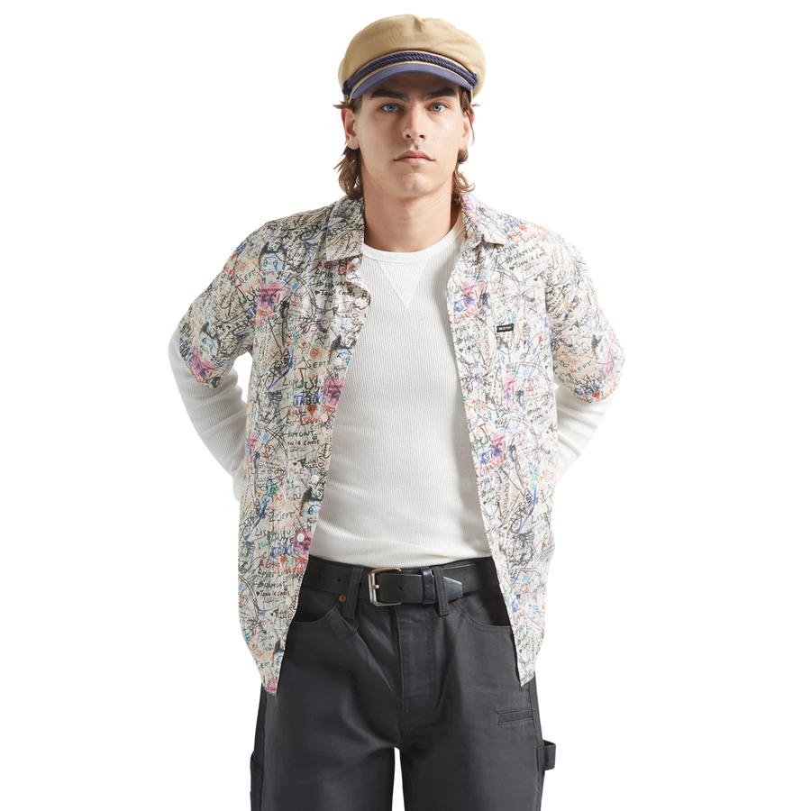 man wearing a brixton cru short sleeve woven shirt with graffiti pattern on a white background