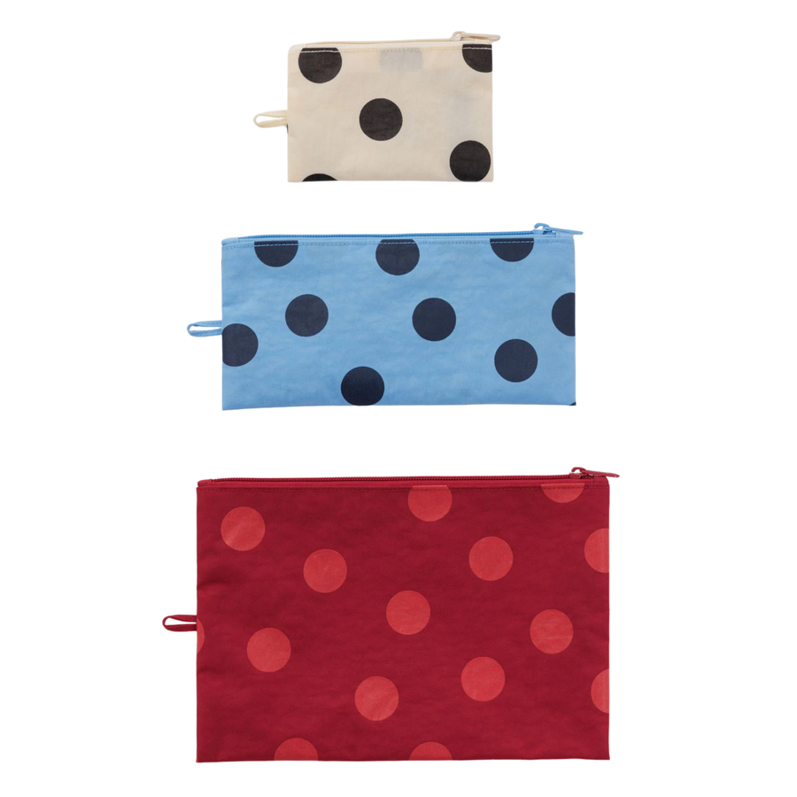 Three zippered baggu flat pouches with polka dot patterns stacked vertically on a white background. The top pouch is cream with black dots, the middle is light blue with dark blue dots, and the bottom is red with pinkish-red dots.