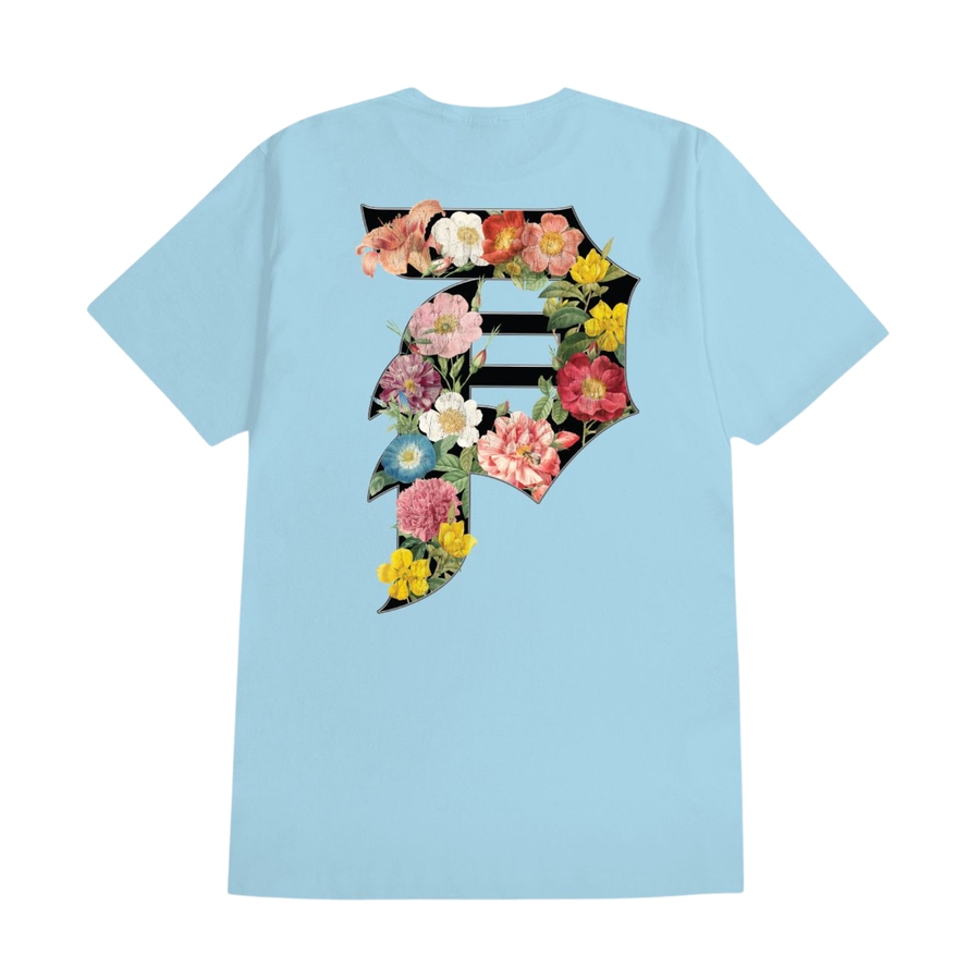 A light blue short-sleeve crewneck t-shirt with a 'Primitive' logo printed on the chest, displayed flat against a solid white background.
