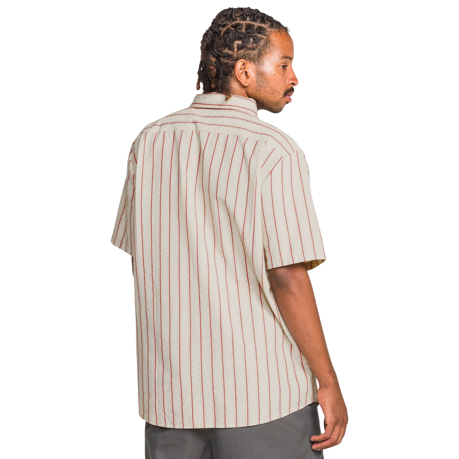 Man wearing a beige and red striped volcom sato stripe short sleeve shirt on a white background