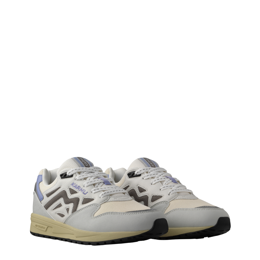 A low-top Legacy 96 sneaker by KARHU in light gray and off-white, featuring a lavender purple heel accent, dark gray side stripes, and a beige midsole.