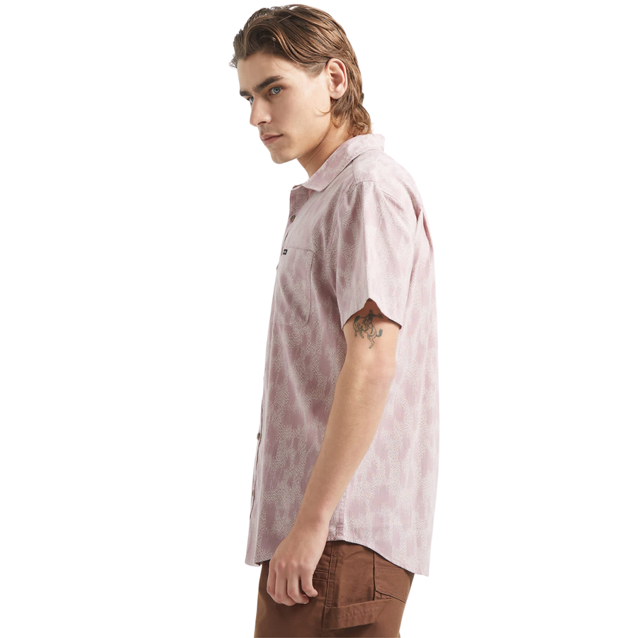 Man wearing a pink brixton charter print patterned short sleeve shirt with brand logo on a white background