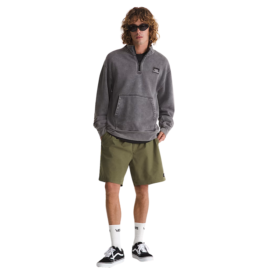 Man wearing a gray pullover, green shorts vans range sport short, and black sneakers on a white background