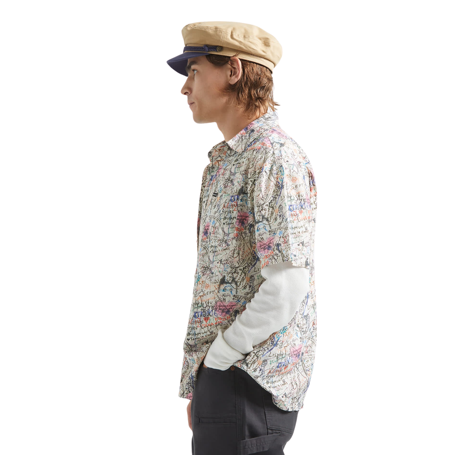 man wearing a brixton cru short sleeve woven shirt with graffiti pattern on a white background