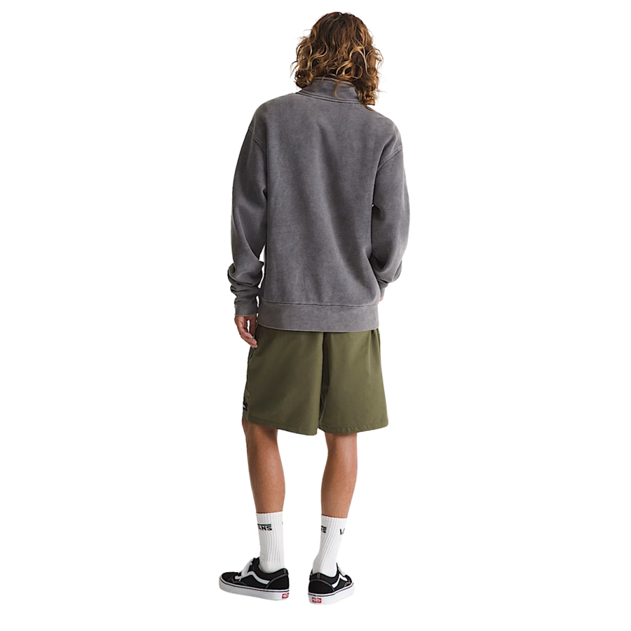 Man wearing a gray pullover, green shorts vans range sport short, and black sneakers on a white background