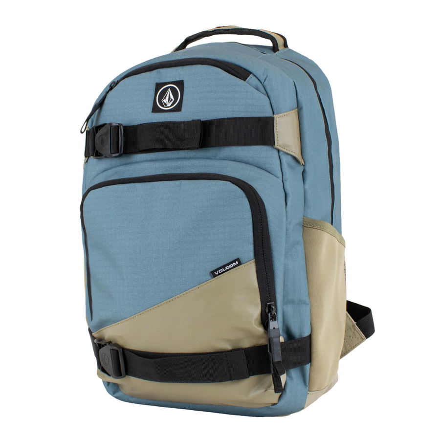 A Volcom grindstone skateboard backpack in slate blue and tan with black straps and zippers, shown against a plain white background.