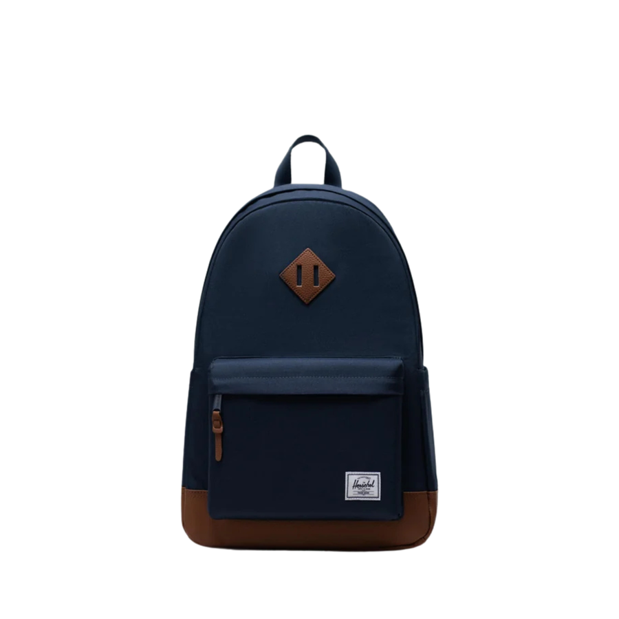 Navy herschel heritage backpack with tan leather bottom and details on a white background