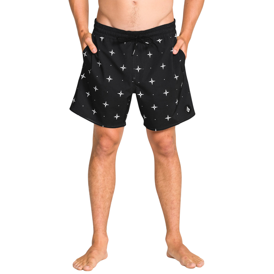 Man wearing black volcom lido swim shorts with star pattern on a white background