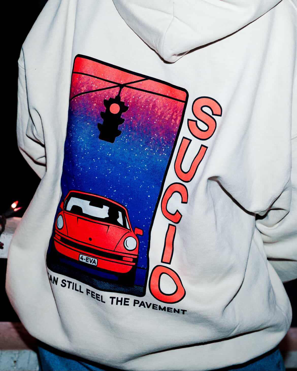 Hoodie with a graphic design of a red car and traffic light, with the word 'Sucio' on a white background.