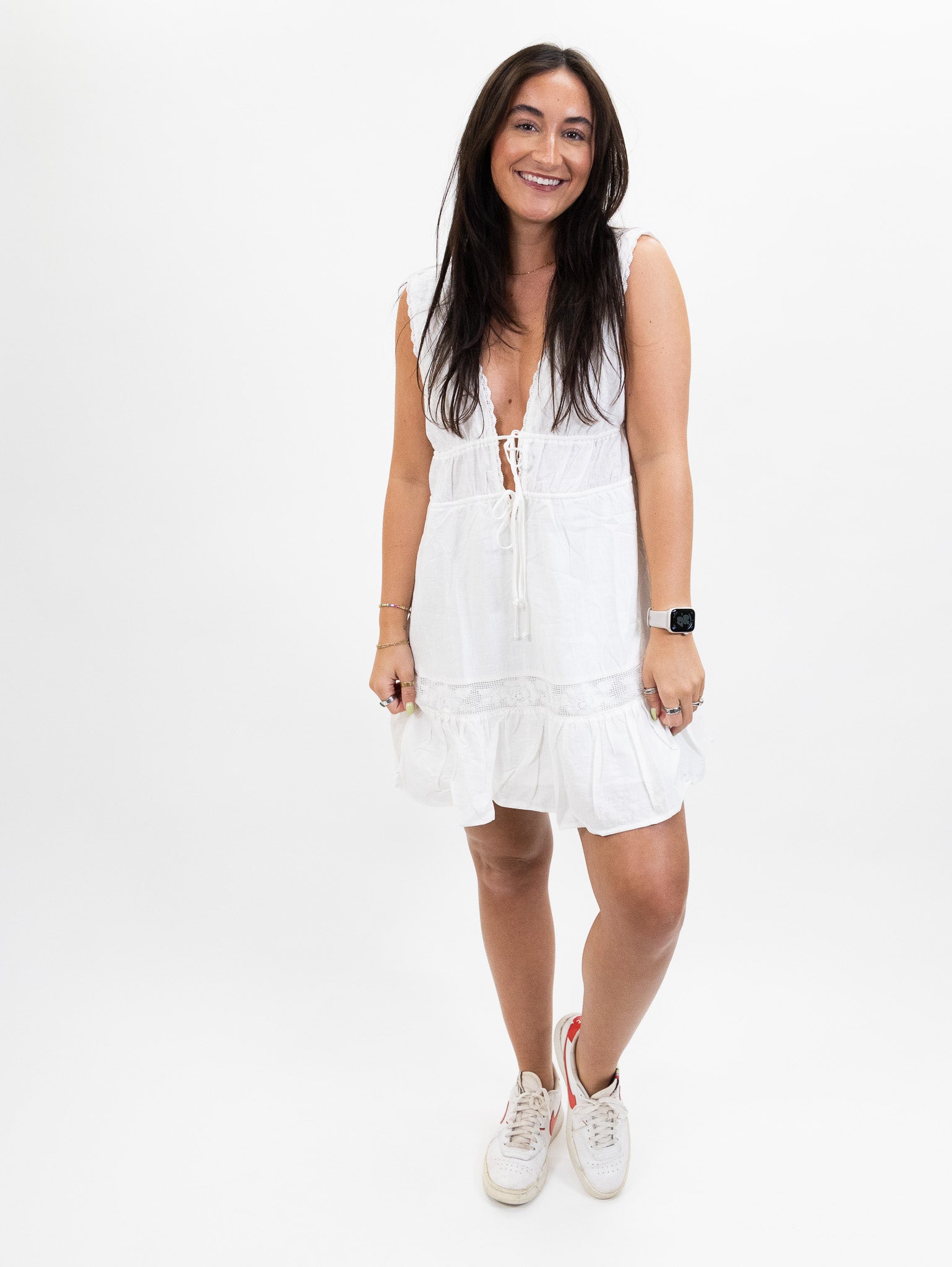 white nia Linen mini dress featuring a plunging neckline, pockets, and self tie adjusters with a Ruffle hem
