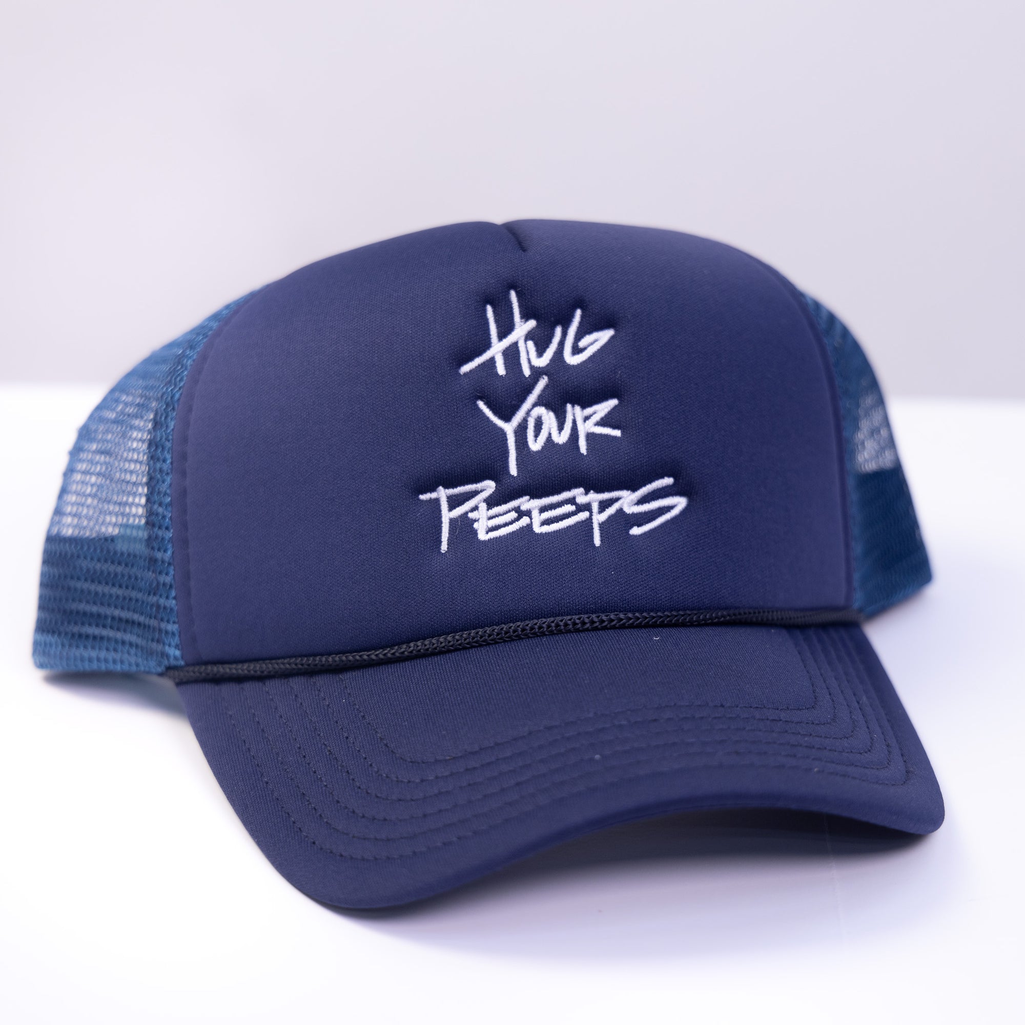 blue trucker hat with the slogan hug your peeps