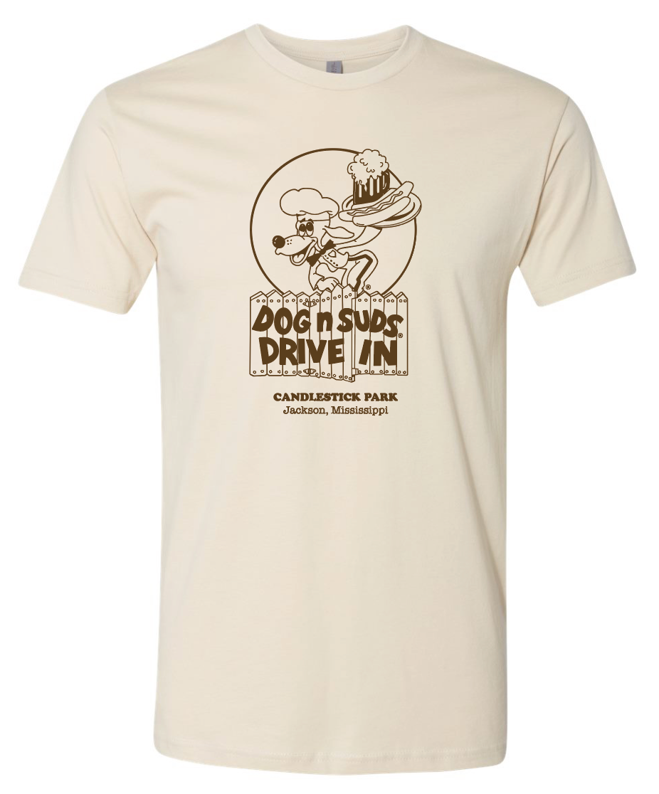 Beige dog n suds drive in candlestick park jackson ms t-shirt with a graphic design of a cartoon dog holding a beet and hotdog on a tray character and text on a white background
