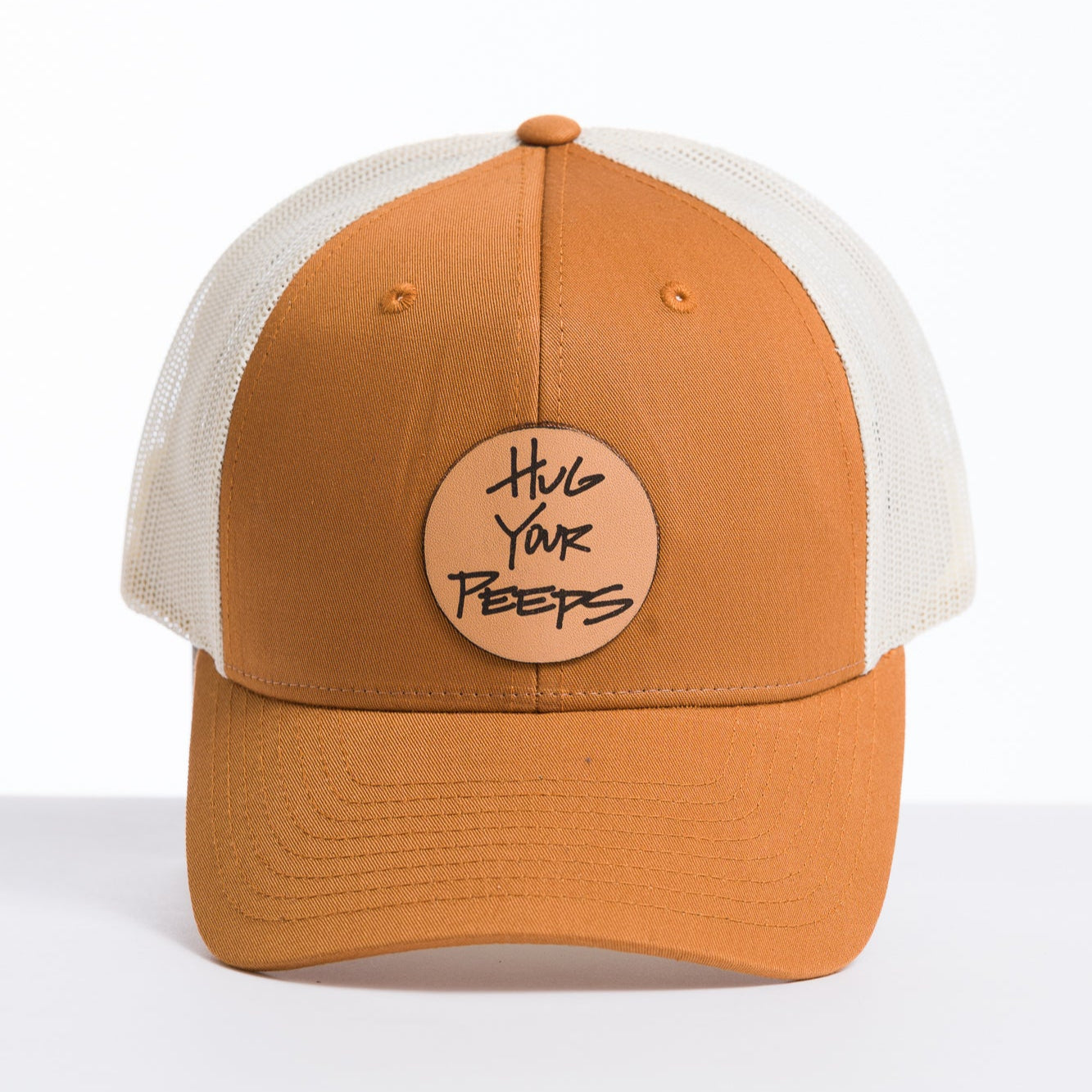 orange and white trucker hat with a hug your peeps leather patch on the front panel