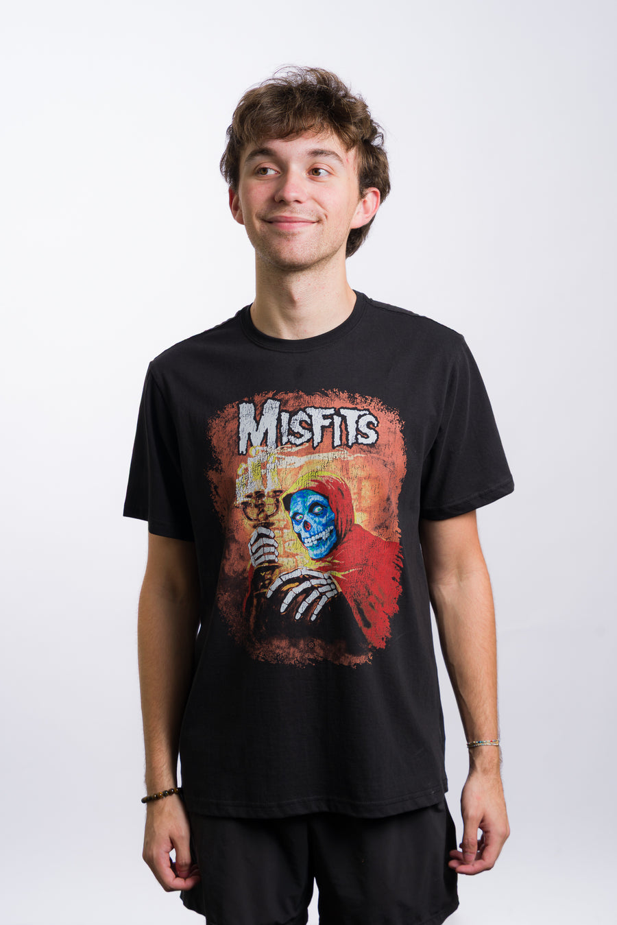 Person wearing a black t-shirt with 'Misfits' graphic design on a white background