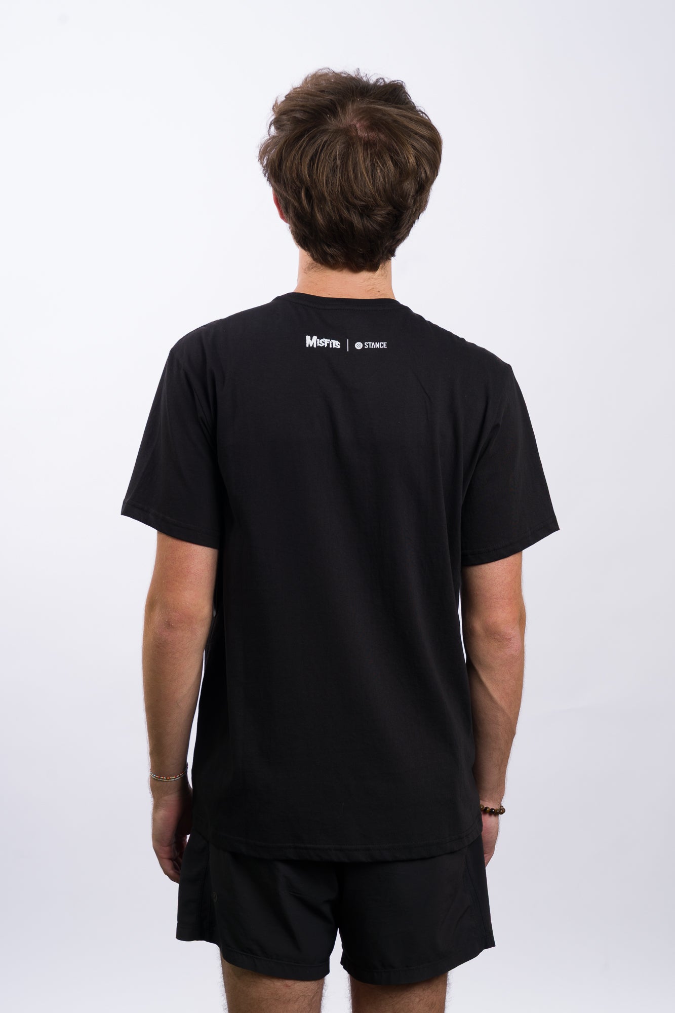 Person wearing a black t-shirt with 'Misfits' graphic design on a white background