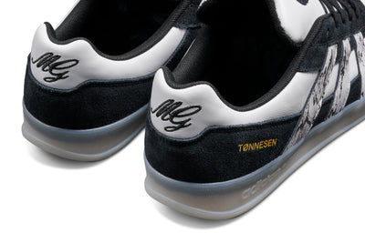 Black and white adidas x gustav tonnesen aloha sneaker with Adidas logo and a clear sole on a white background