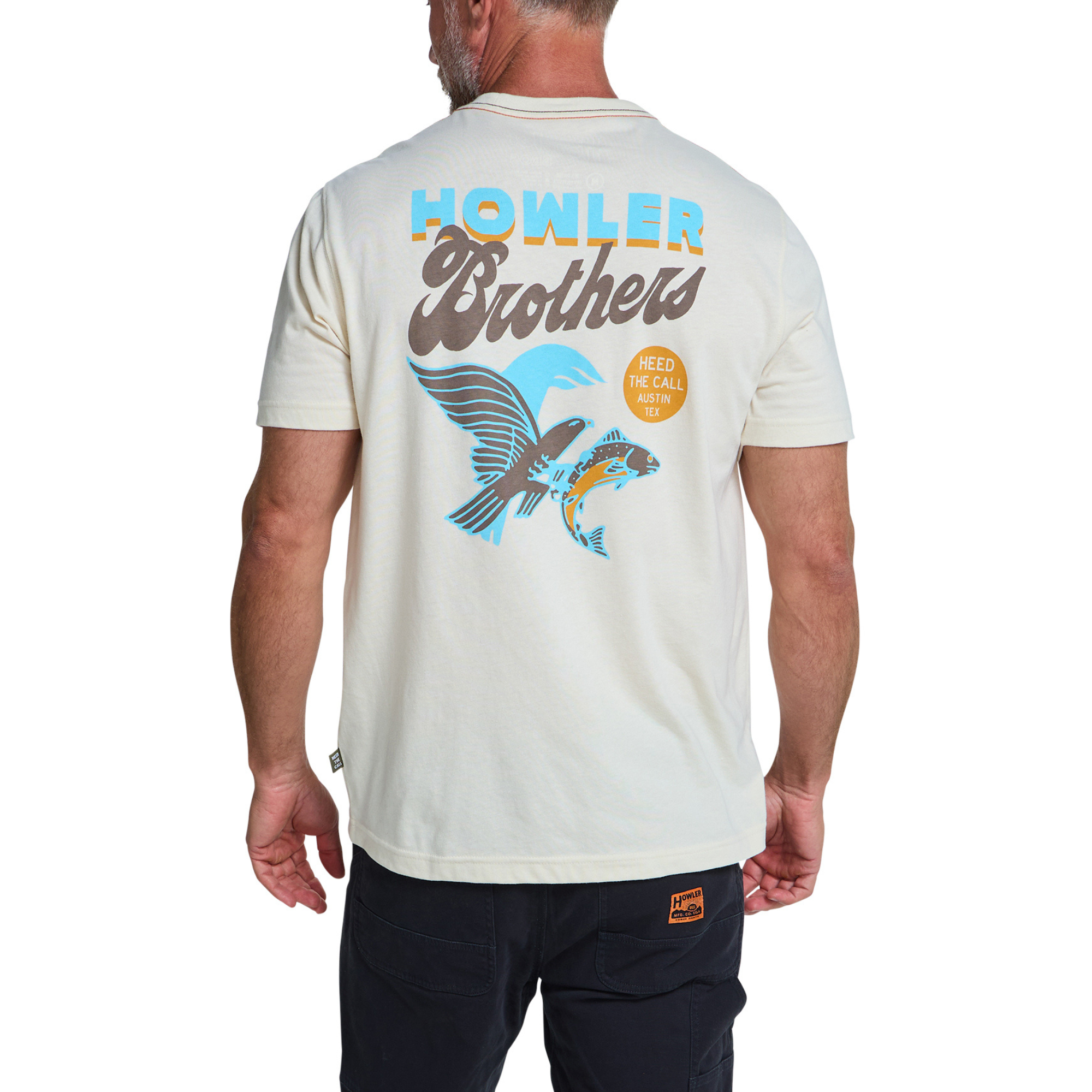 A man viewed from the back wearing a cream-colored t-shirt with a large graphic on the back. The graphic features the text 'HOWLER Brothers' in blue and brown, above a blue and yellow fish design.