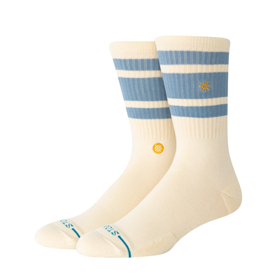 A pair of Stance got sol crew socks in cream with light blue horizontal stripes near the cuff, a small yellow logo on the side, and teal lettering on the toes, shown against a plain white background.