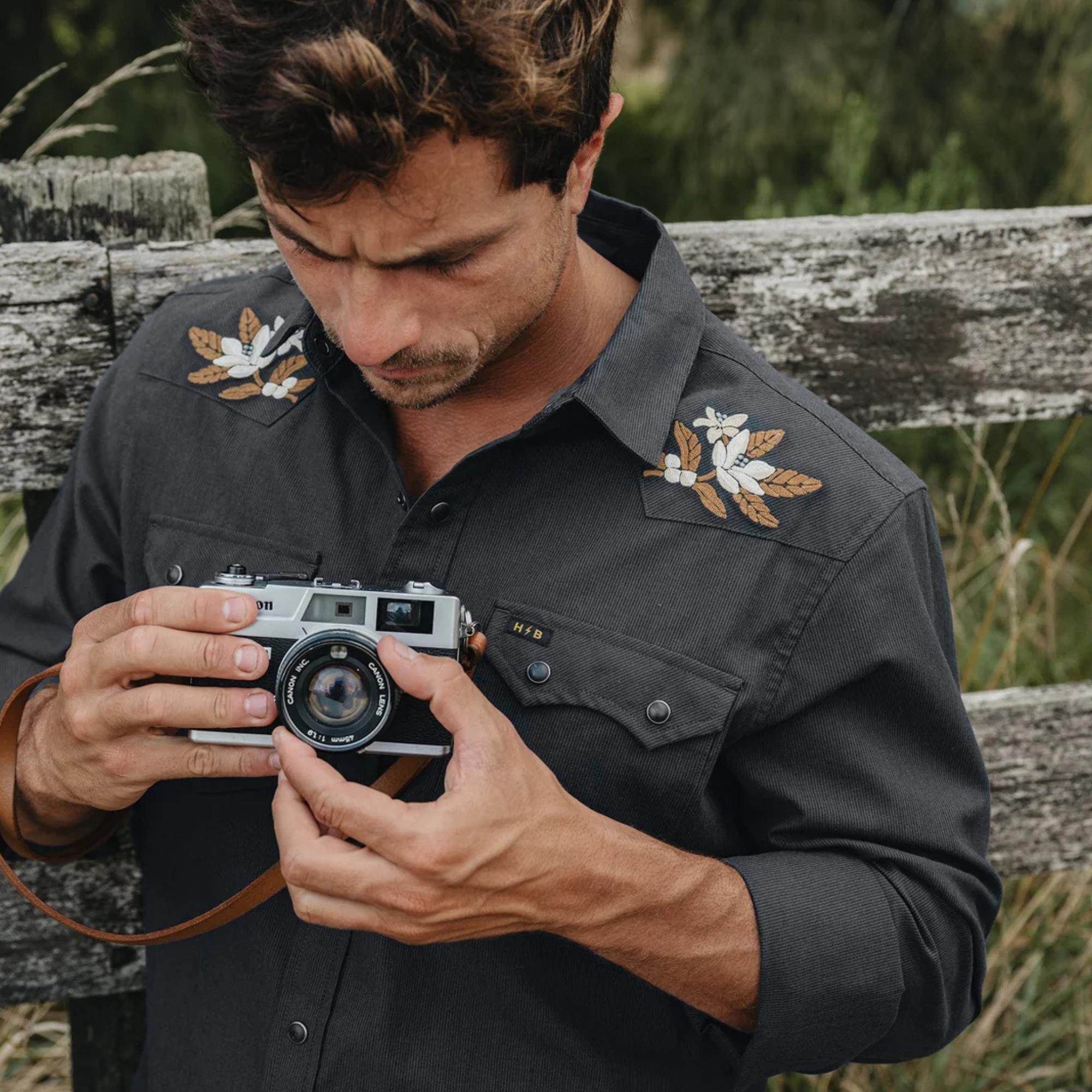 man wearing a howler dark navy western-style button-up shirt with embroidered eagle details on the shoulders and beige pants, photographed against a plain white background.