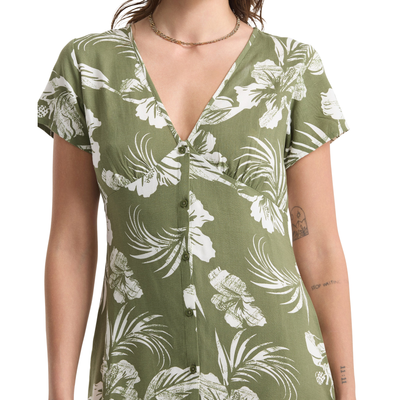 Woman wearing a green volcom vroom service dress with white floral pattern on a white background
