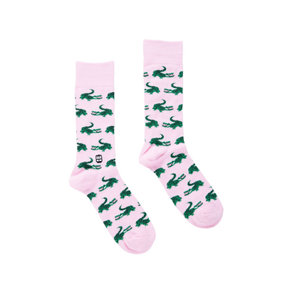 Pink bonfolk socks with green alligator pattern on a white background