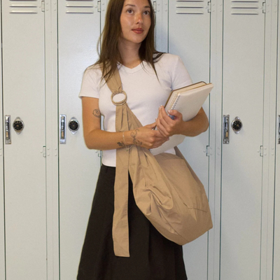 Woman holding a beige bag and notebook in front of lockers