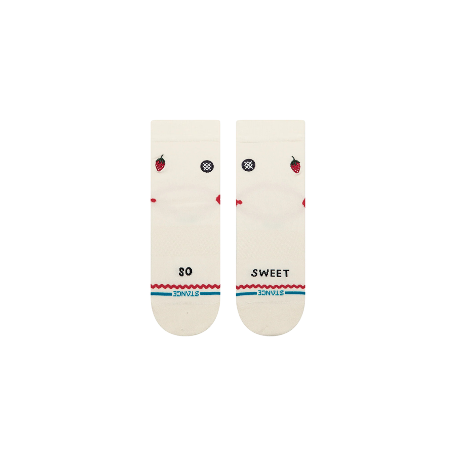 A pair of Stance crew socks in off-white, featuring a black circular logo with a white cross on the front ankle, a small red strawberry graphic on the side, and red and blue wavy stripe accents near the toe.