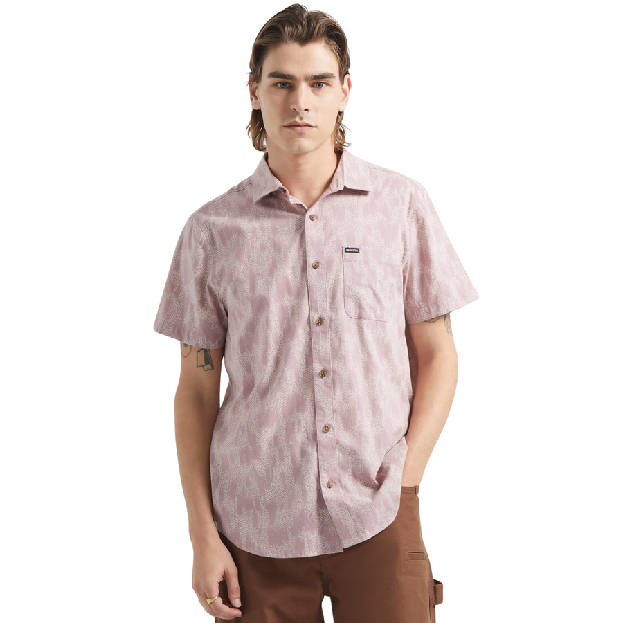 Man wearing a pink brixton charter print patterned short sleeve shirt with brand logo on a white background