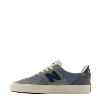 A pair of New Balance 340 low-top sneakers in a muted blue-gray suede and canvas mix, featuring off-white laces and a thick off-white rubber sole, with a small red accent visible inside the heel collar.