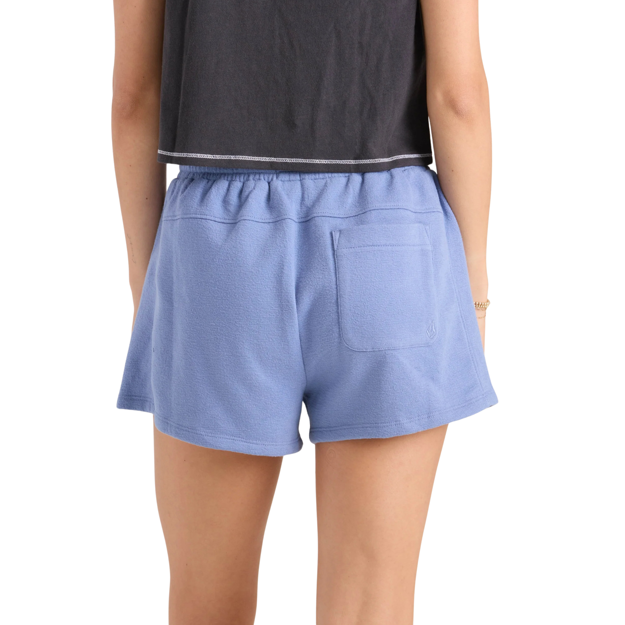 Person wearing blue volcom lived in fleece shorts and a black crop top with graphic design on a white background