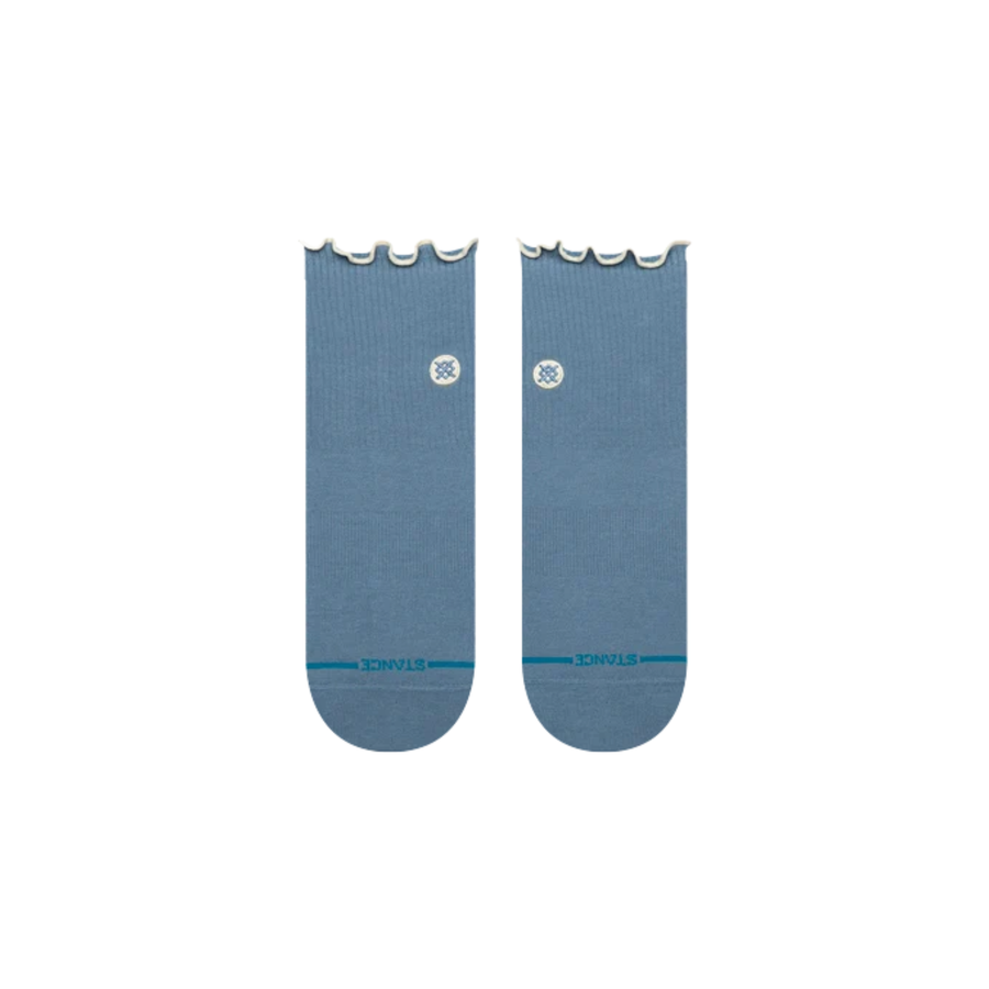 A pair of stance light blue ankle socks with scalloped ruffle edges at the top and a small white circular logo on the side, displayed against a plain white background.
