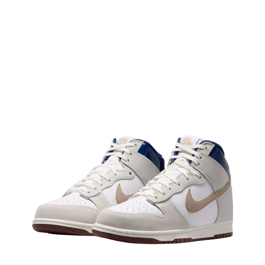 A Nike SB X Beyond Skate Shop Dunk High sneaker in off-white leather with a beige Swoosh, a blue collar lining, and a brown gum outsole, shown from a side profile on a white background.