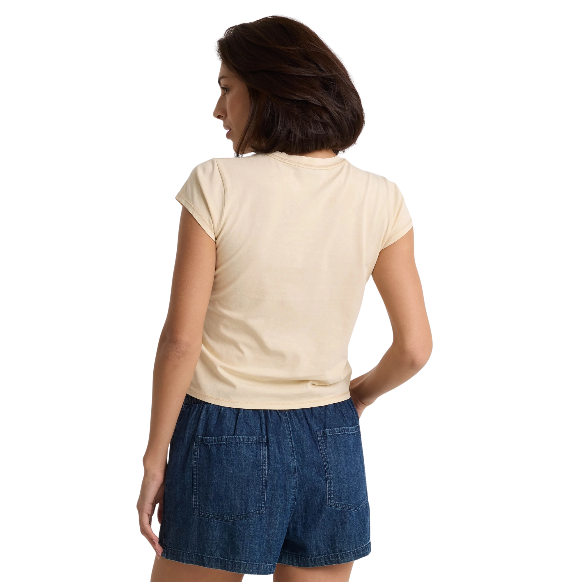 Woman wearing a beige volcom lived in stone wash t-shirt and blue shorts on a white background