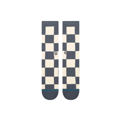 A pair of stance chaturanga crew socks with a blue-gray and cream checkerboard pattern, featuring a small circular Stance logo on the side and a thin teal stripe on the toes.