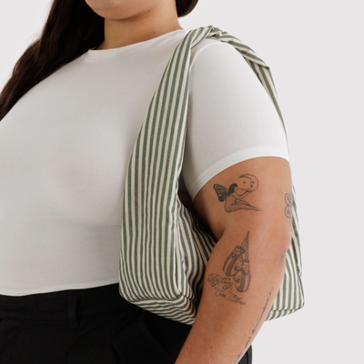 Person wearing a sage Striped baggu small meringue nylon handbag on a white background