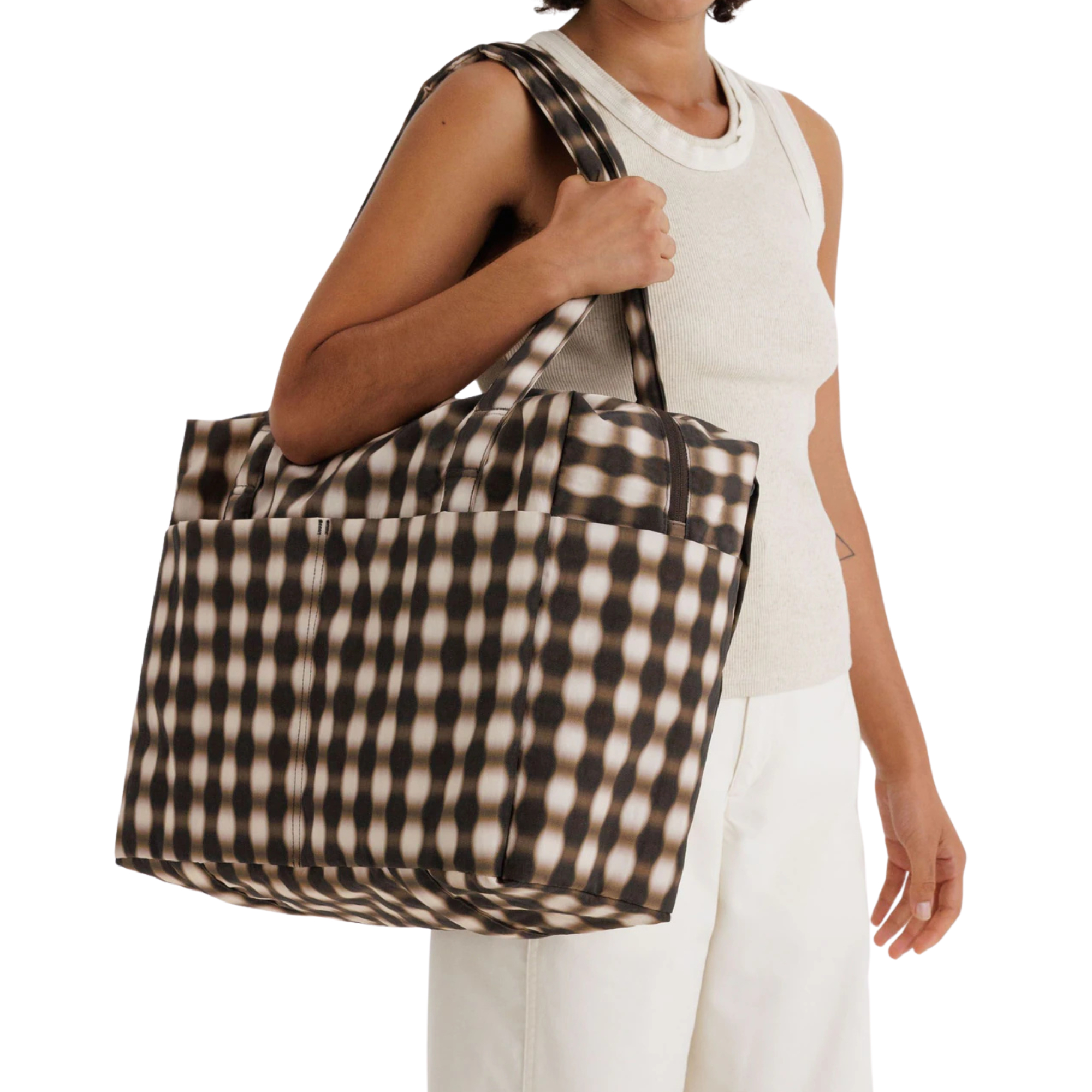 Person holding a large checkered bag on a white background