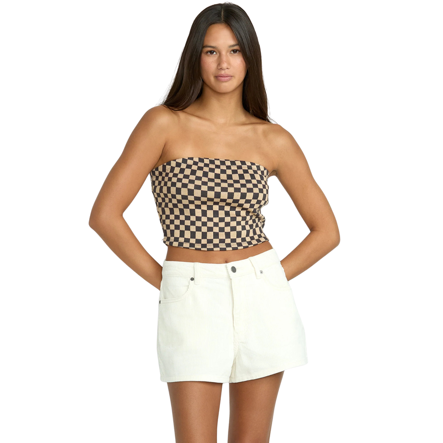 Woman wearing a checkered strapless top and white volcom straight up shorts on a white background