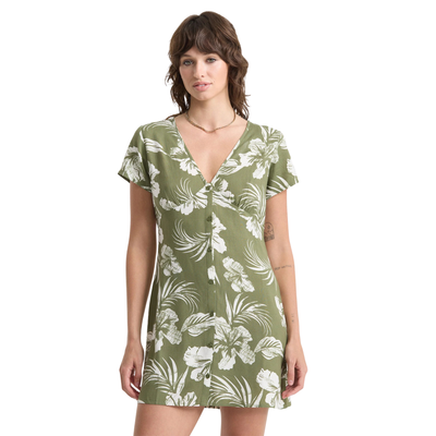 Woman wearing a green volcom vroom service dress with white floral pattern on a white background