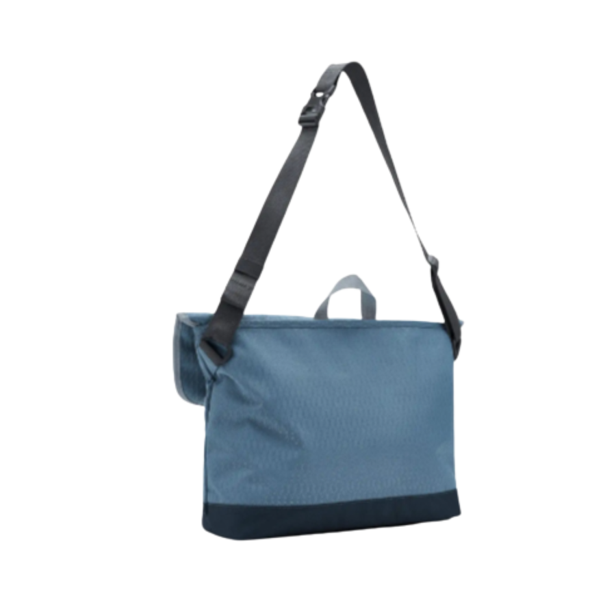 Blue herschel cove messenger bag with a black strap on a white background