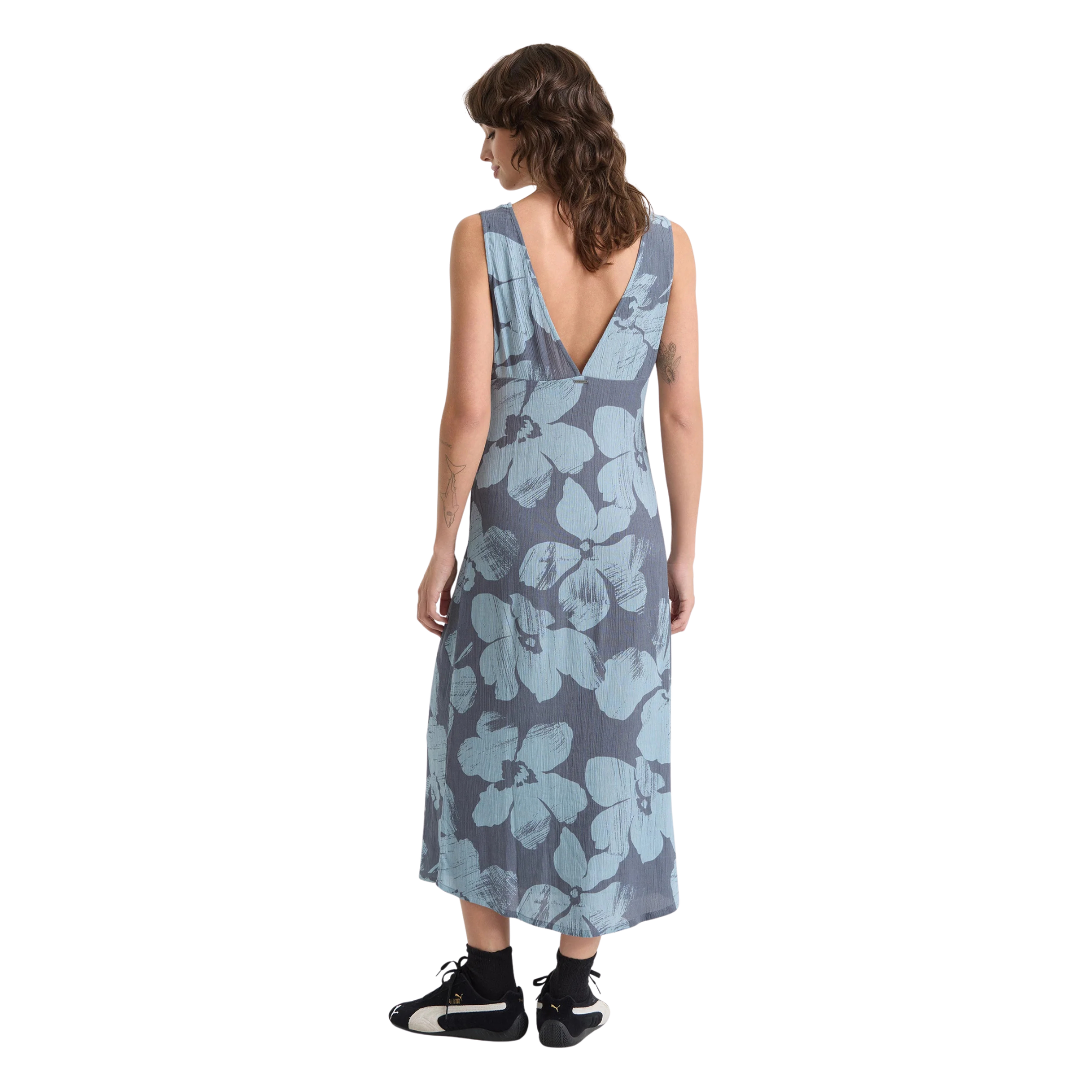 Woman wearing a sleeveless volcom grumpy sunshine floral dress on a white background