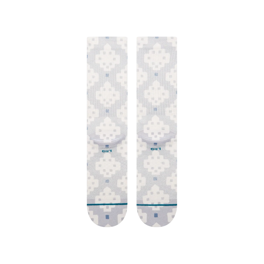 A pair of Stance alhambra butterblend crew socks with a light gray and white pixelated geometric pattern, featuring a small blue logo and 'STANCE' branding on the toes.