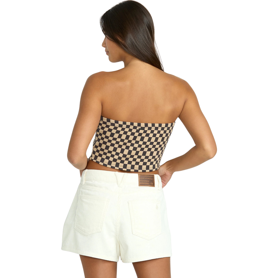 Woman wearing a checkered strapless top and white volcom straight up shorts on a white background
